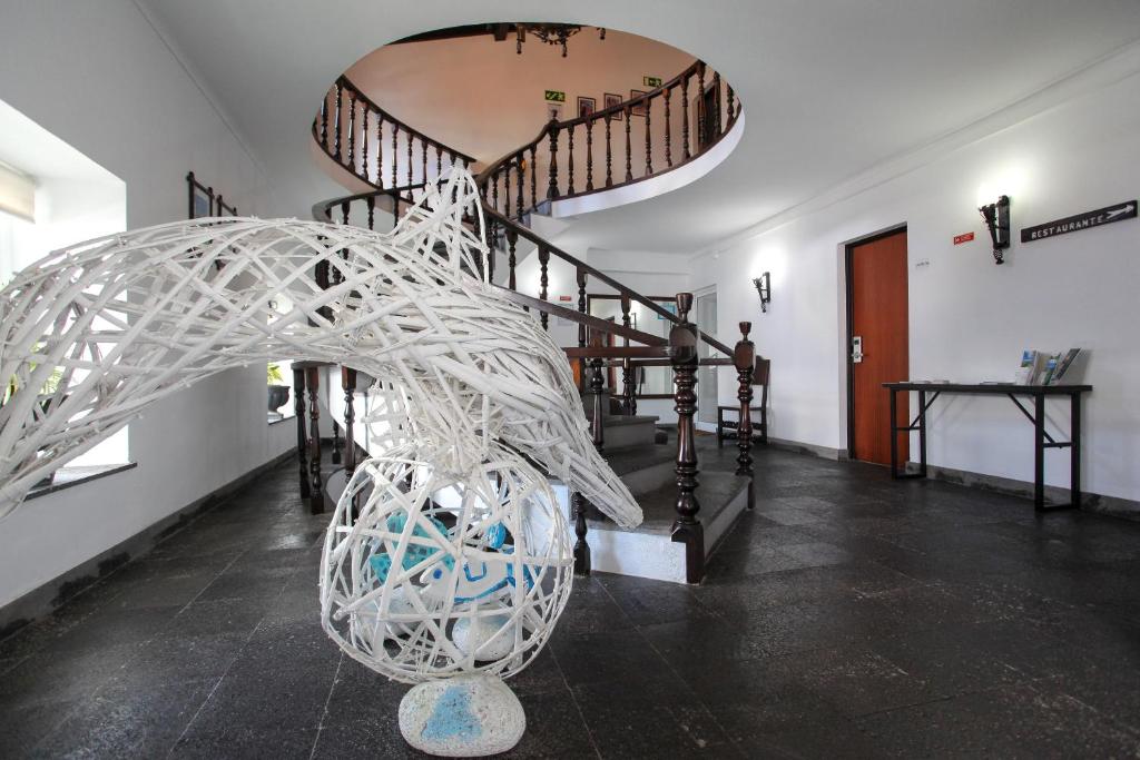 a hallway with a spiral staircase with a white sculpture at Aparthotel Barracuda in Ponta Delgada