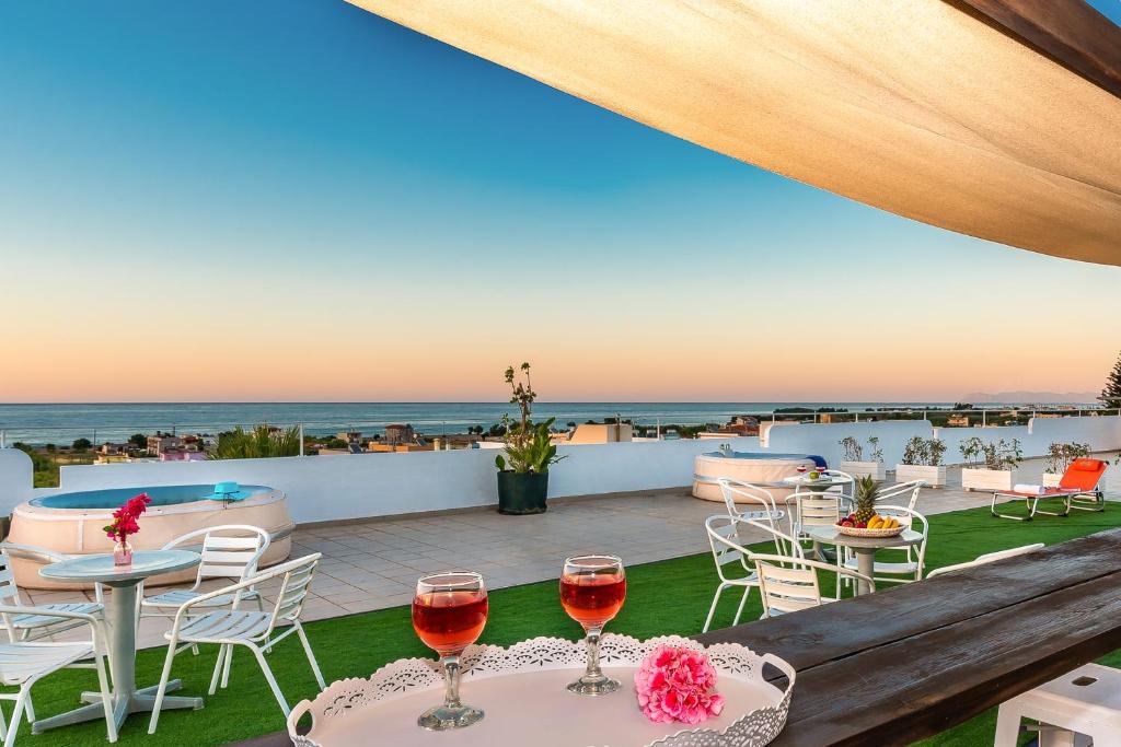 eine Terrasse mit zwei Gläsern Wein auf dem Tisch in der Unterkunft Louladakis Apartments in Kolimvárion