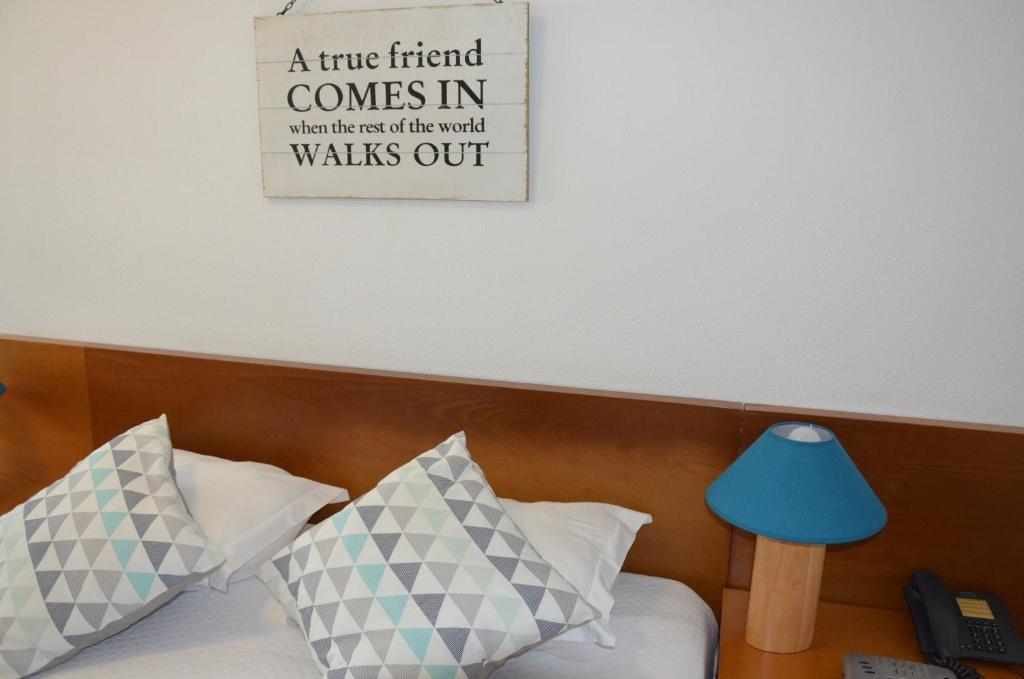 a sign on the wall above a bed with pillows at ABLA Guest House in Carcavelos