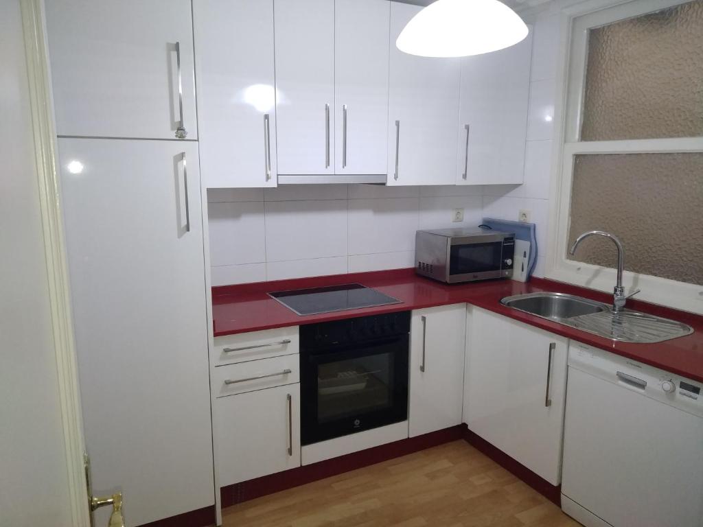 cocina con armarios blancos y encimera roja en YEDRA, en Ourense
