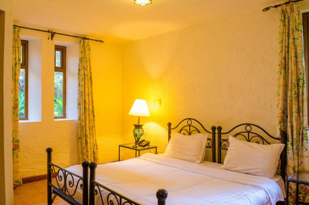 - une chambre avec un lit doté de draps blancs et d'une lampe dans l'établissement Kianderi Villa-Great Rift Valley Resort, à Naivasha