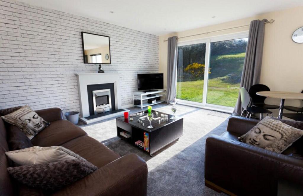 a living room with two couches and a fireplace at Valley Lodge in Trearddur