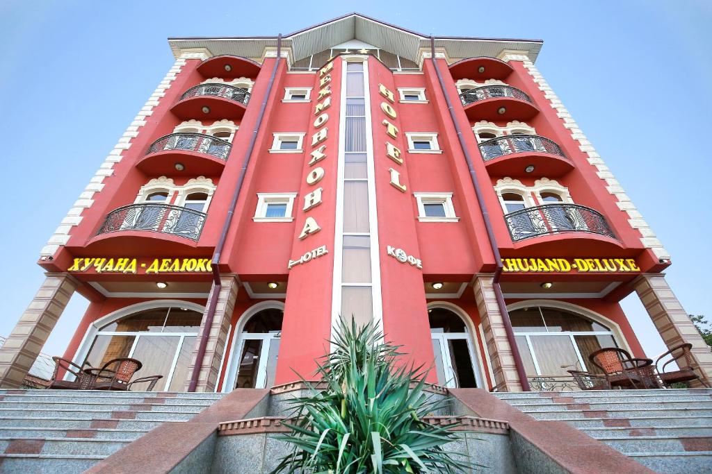 um edifício vermelho com varandas ao lado em Khujand Deluxe Hotel em Khujand