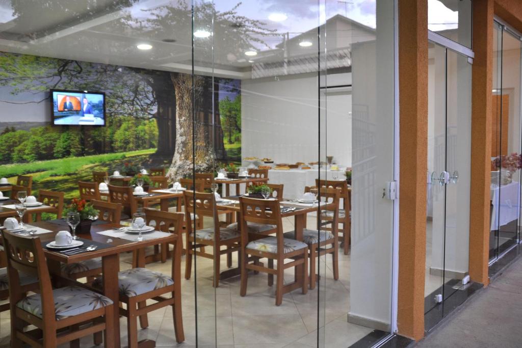 a restaurant with wooden tables and chairs and a wall mural at Pousada Shangrila in Ribeirão Preto