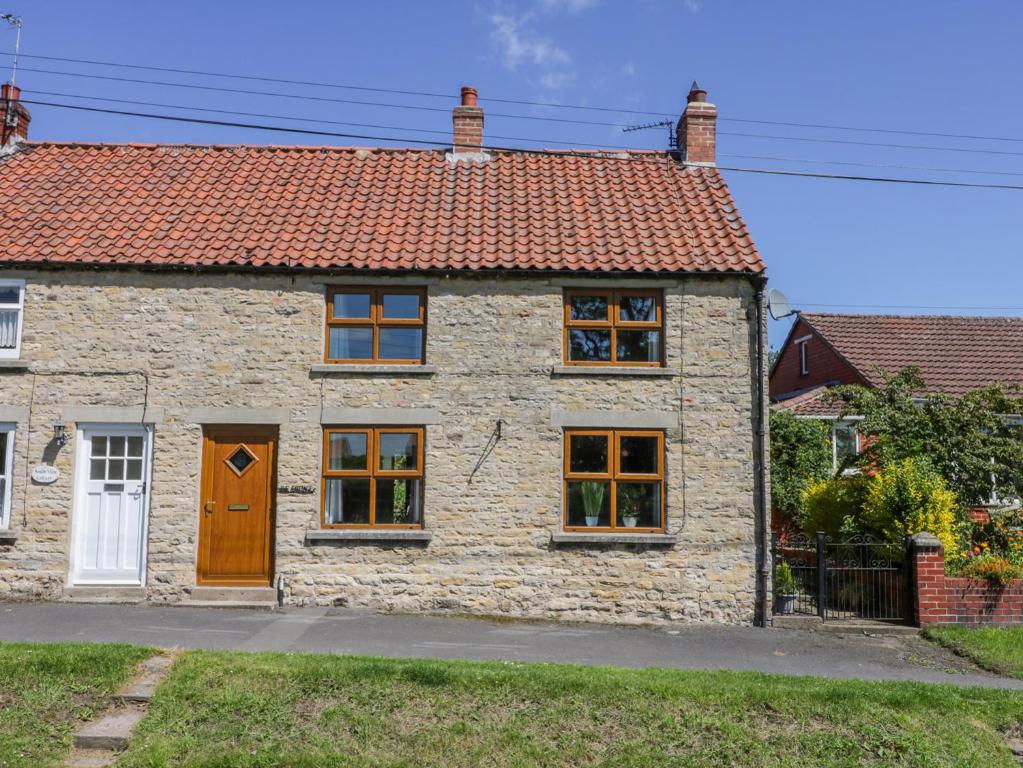 a stone house with a brown door and windows at The Cottage in Pickering