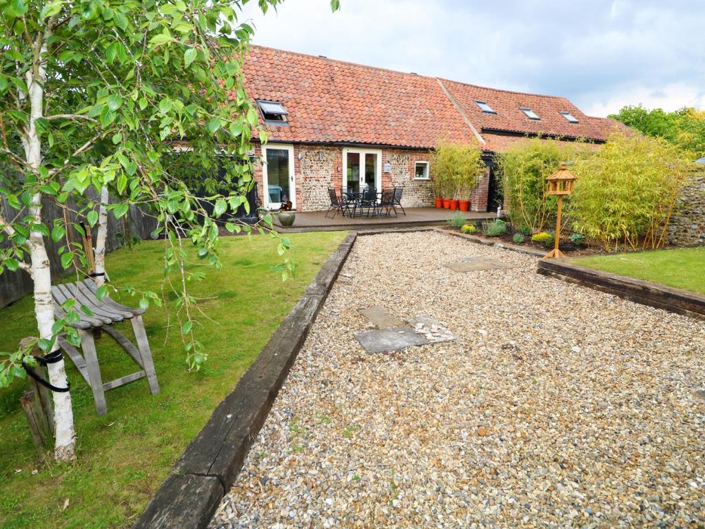a garden with a bench and a house at Far Barn in Fakenham