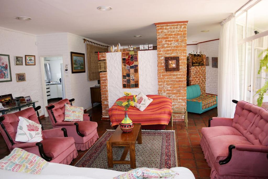 Elle comprend un salon doté d'un mobilier rose et d'un mur en briques. dans l'établissement Fleming Place, à Bulawayo