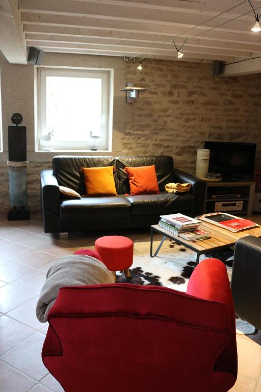 a living room with a black couch and orange pillows at Gite Le Meix Chapeau in Levernois