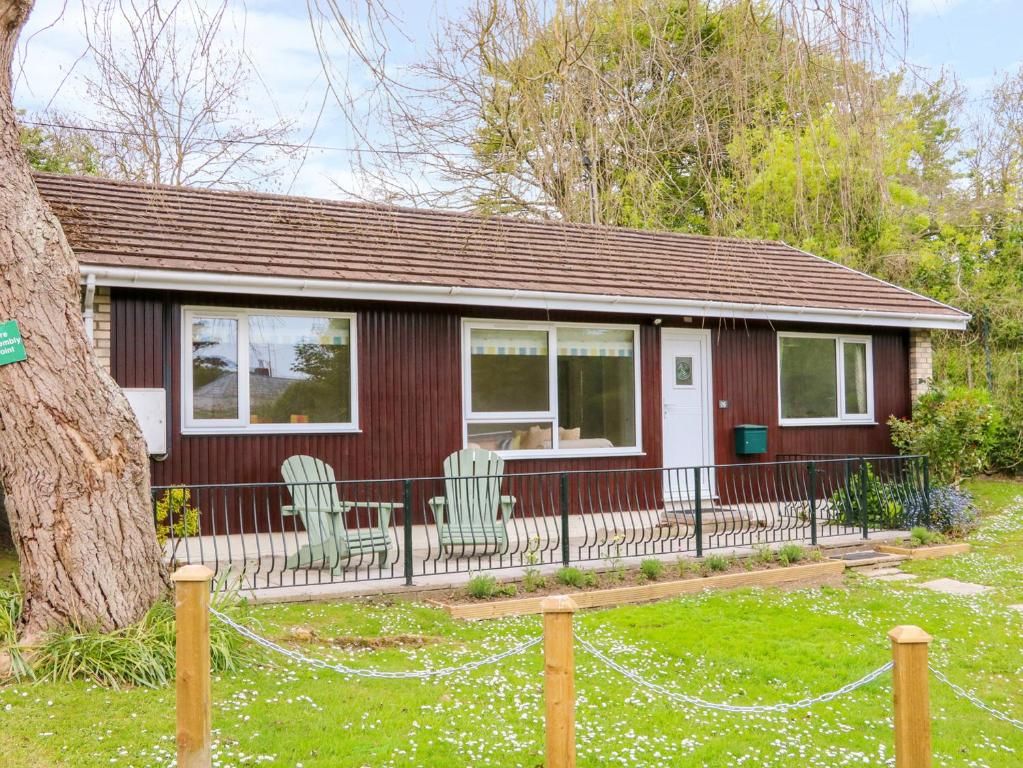 a small house with two chairs and a fence at Lavender Lodge in Bideford