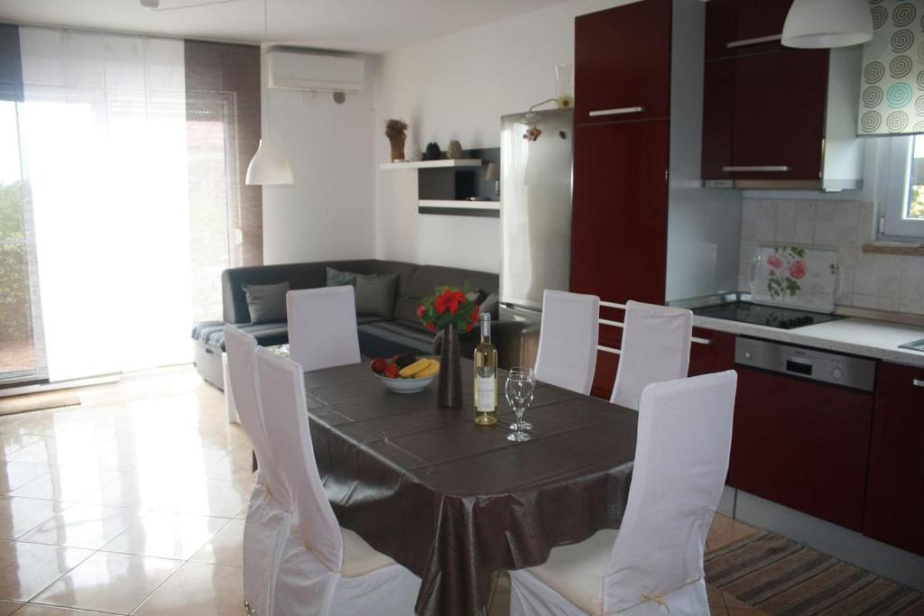 eine Küche mit einem Tisch mit weißen Stühlen und einem Esszimmer in der Unterkunft Apartman Antonia in Poreč