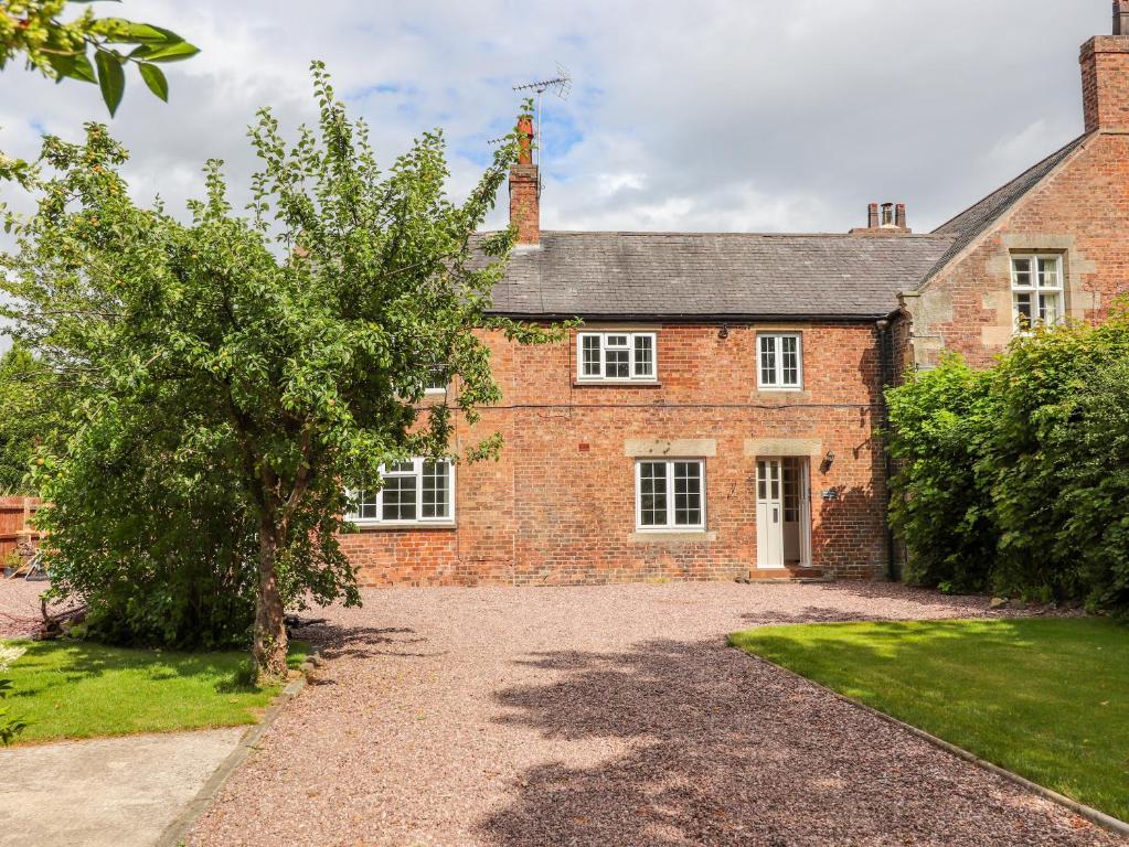 an old brick house with a tree in front of it at Well House Farm Flat 1 in Chester