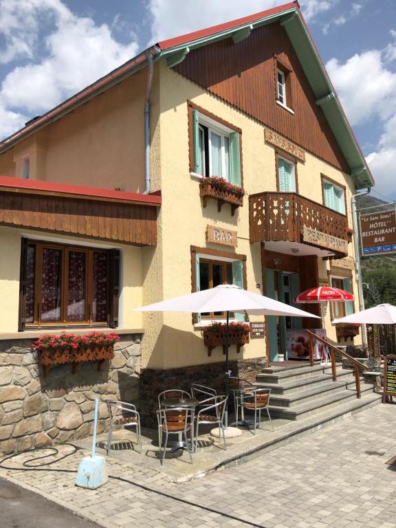 a building with chairs and umbrellas in front of it at Hôtel Sans Souci in Jausiers