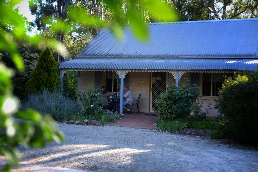 two people sitting at a table on the porch of a house at Donnybrook Cottages - Hutt River in Clare