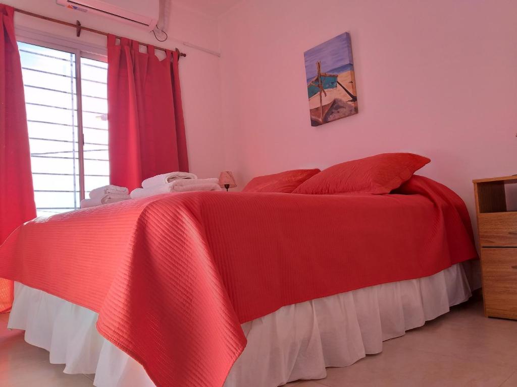 1 cama roja y blanca en una habitación con ventana en MAPE Departamentos en San Rafael