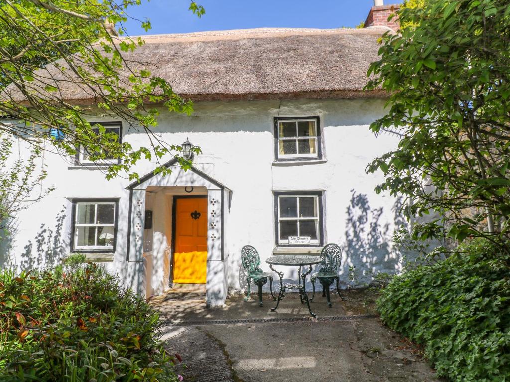 彭贊斯的住宿－The Thatched Cottage，白色的房子前面设有桌椅