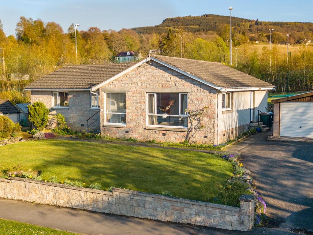 a brick house with a dog in a window at Cromallt in Aberfeldy