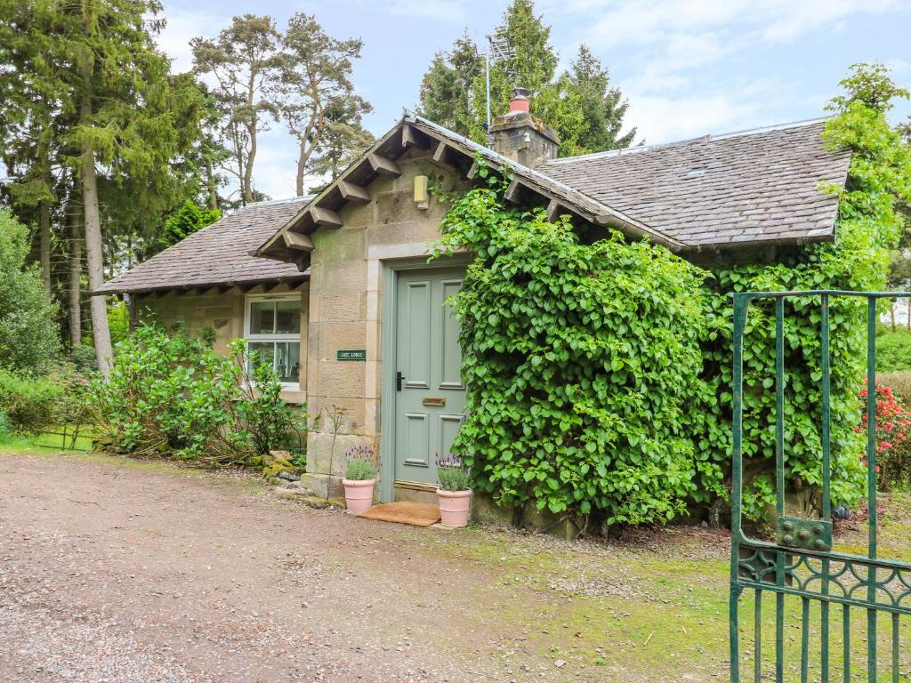 una pequeña casa con una puerta verde en Gate Lodge en West Calder