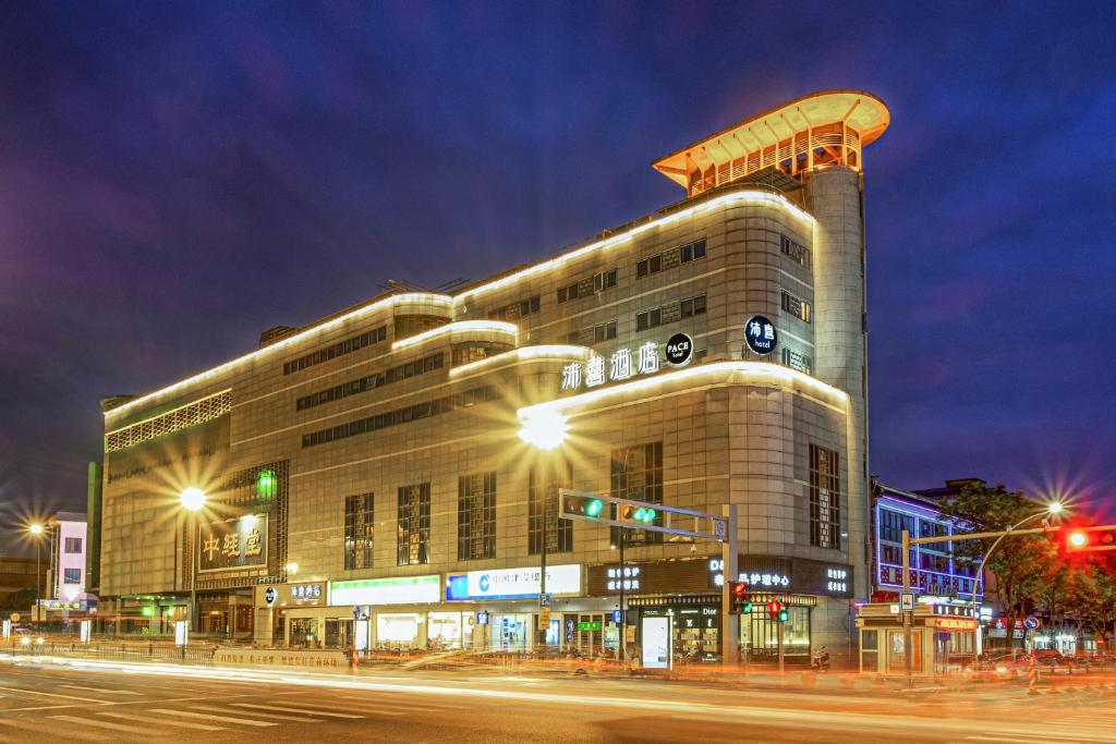 un grand bâtiment situé dans une rue de la ville la nuit dans l'établissement PACE HOTEL Suzhou Renmin Branch, à Suzhou