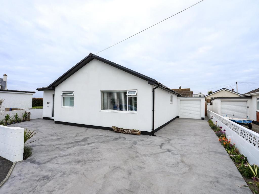 a white house with a driveway at Ling Di Long in Rhosneigr