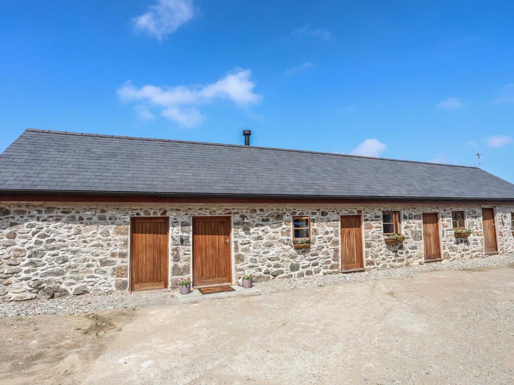 a stone building with wooden doors on it at Y Bwthyn in Llanfairpwllgwyngyll