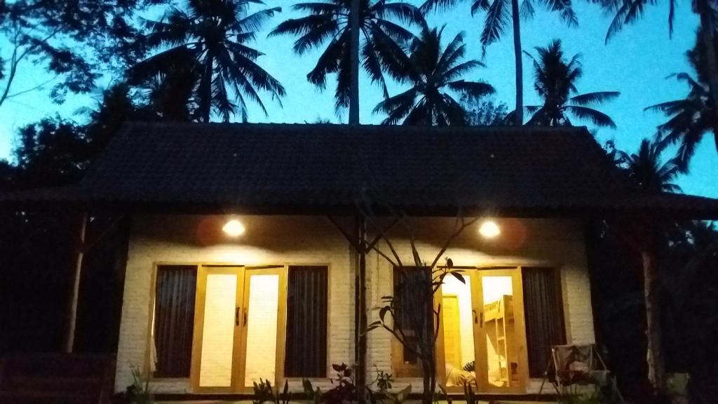 a small house with palm trees at night at Jungle House - surf & stay in Pulukan