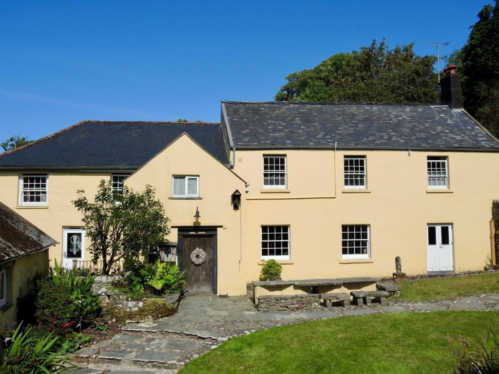 a large yellow house with a courtyard at Holwell Holistic Retreat in Barnstaple