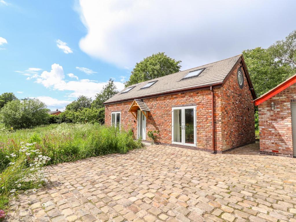 a brick house with a driveway in front of it at The Stables in Frodsham