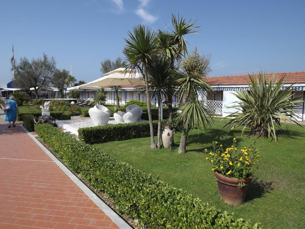 a garden with palm trees and plants and a house at Bed & Breakfast Venezia in Marina di Carrara