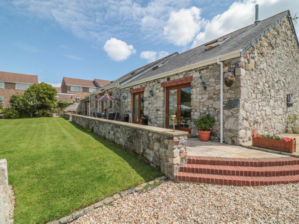 a stone house with a stone wall at Woodside Barns in St Austell