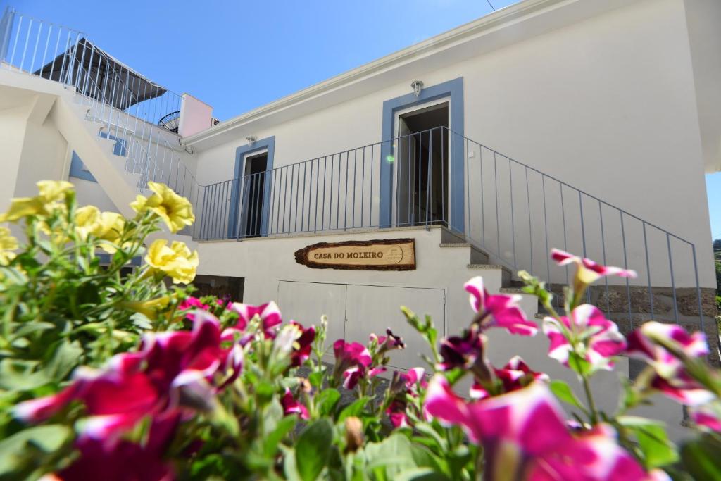 Casa do Moleiro في أمارانتي: مبنى أبيض أمامه زهور أرجوانية