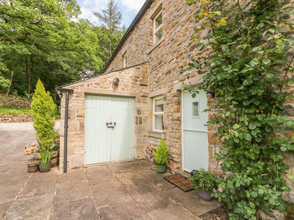 ein Steinhaus mit einer weißen Garage in der Unterkunft Spens Farm Cottage in Lancaster