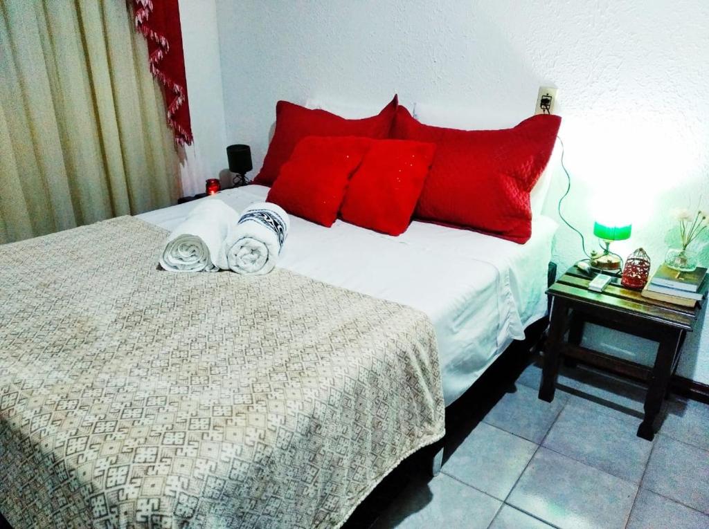 um quarto com uma cama com almofadas vermelhas em Gardenia House em Foz do Iguaçu