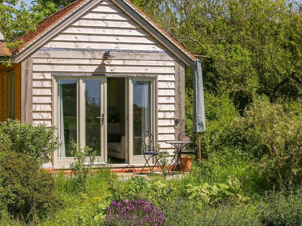 a small house with a table and a chair on the porch at The Lodge at Mortons in Malmesbury