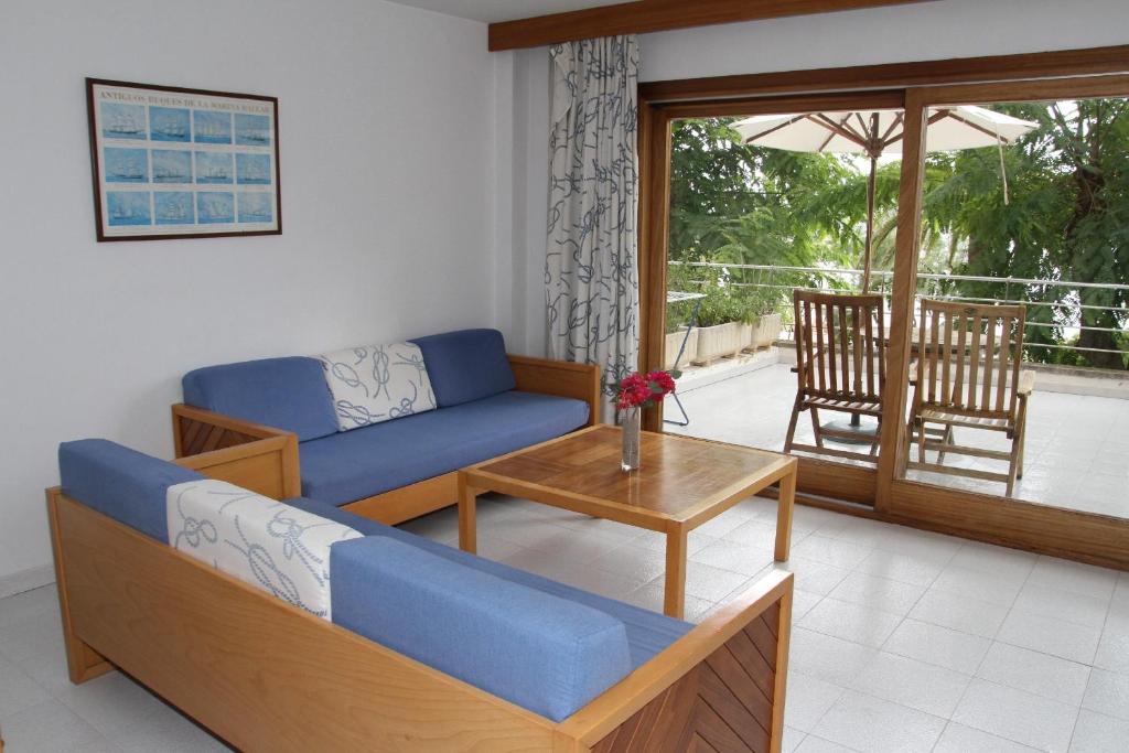 a living room with a blue couch and a table at Apartamentos Marina in Port de Pollensa