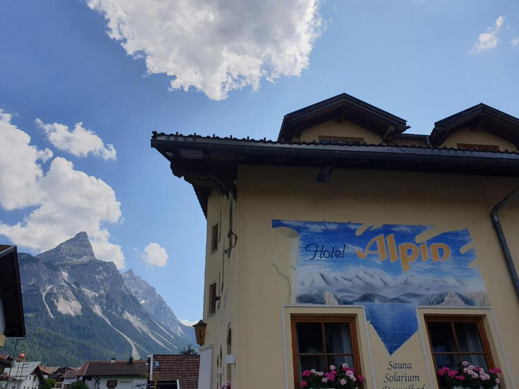 a building with a sign on the side of it with a mountain at Hotel Alpin in Ehrwald
