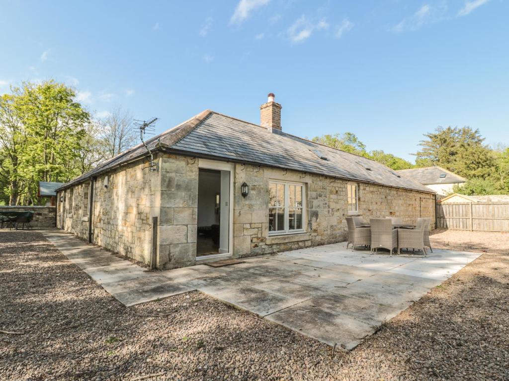 um antigo celeiro de pedra com cadeiras e um pátio em Nursery Cottage em Morpeth