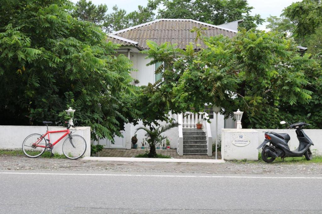 una bicicleta y un scooter estacionados frente a una casa en В ГОСТЯХ У РУСЛАНА, en Gonio