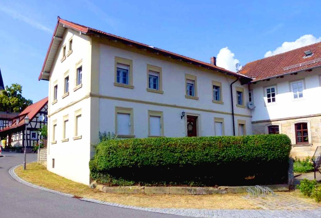 a white house with a hedge in front of it at Villa Merzbach - Wohnen wie im Museum mit Komfort in Untermerzbach