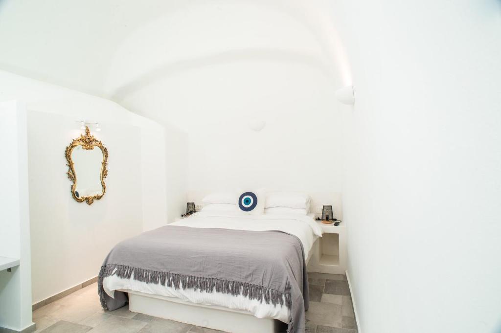 a white bedroom with a bed and a mirror at Mati Cave Villas in Karterados