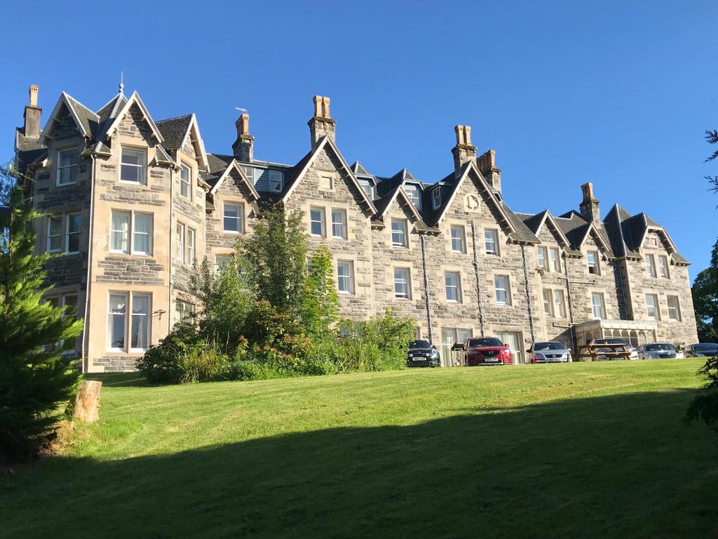 a large building with a green lawn in front of it at Ben Wyvis Hotel in Strathpeffer