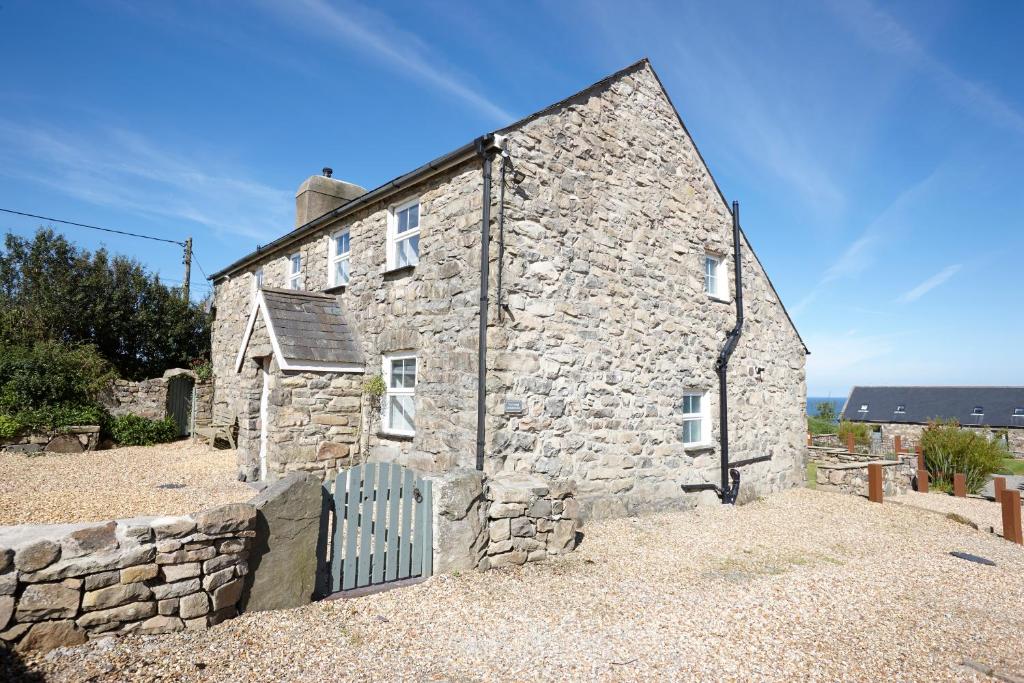 an old stone house with a fence in front of it at The Farmhouse Llyn Peninsula in Pistyll