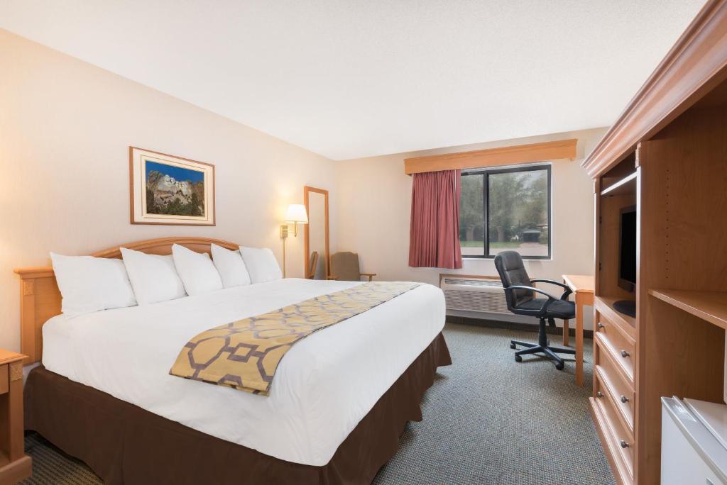 ein Hotelzimmer mit einem großen Bett und einem Fernseher in der Unterkunft Baymont by Wyndham Hot Springs in Hot Springs