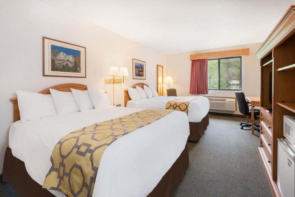 ein Hotelzimmer mit zwei Betten und einem Schreibtisch in der Unterkunft Baymont by Wyndham Hot Springs in Hot Springs
