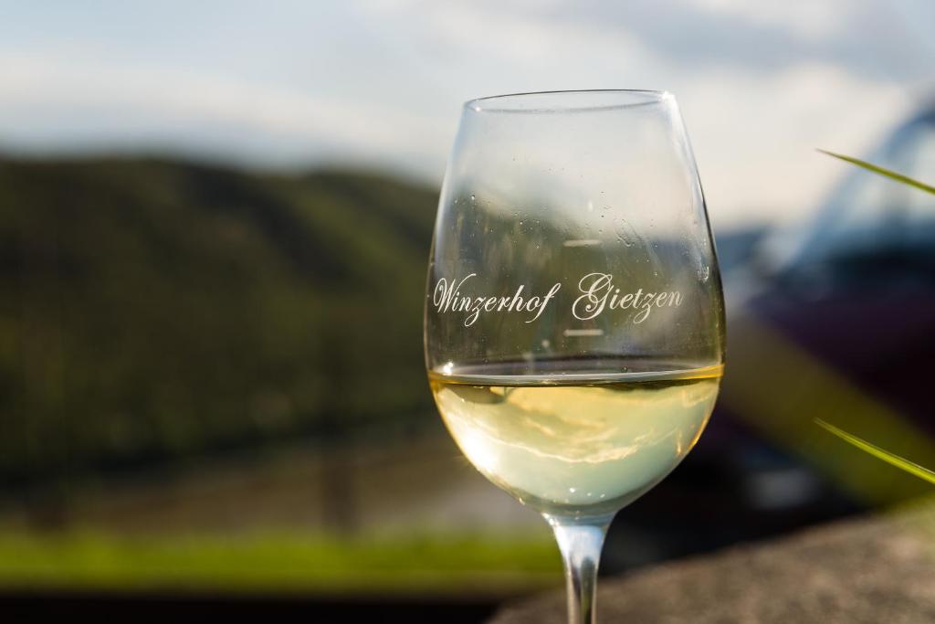 a glass of white wine sitting on a table at Winzerhof Gietzen in Hatzenport