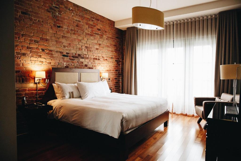 a bedroom with a large bed and a large window at Hotel Nelligan in Montreal