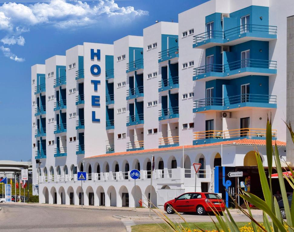 THE FOZ Beach Hotel في فيغيورا دا فوز: مبنى فيه سيارة حمراء متوقفة أمامه