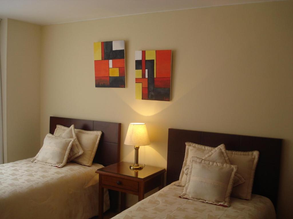 1 dormitorio con 2 camas y mesa con lámpara en Apartamentos Santa Maria, en Bogotá
