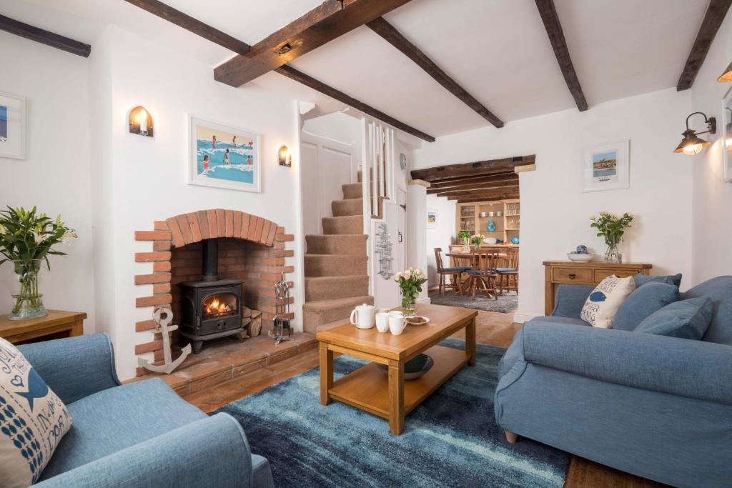 a living room with two blue couches and a fireplace at Fossil Cottage in Whitby