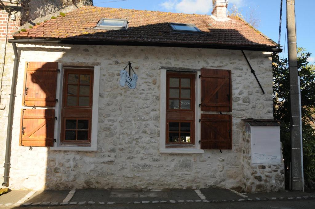 ein weißes Gebäude mit braunen Fensterläden in der Unterkunft Gîte Mi Do in Tourly