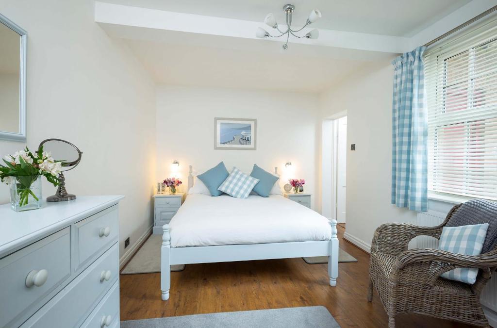 a bedroom with a white bed and a chair at The Riddle in Whitby